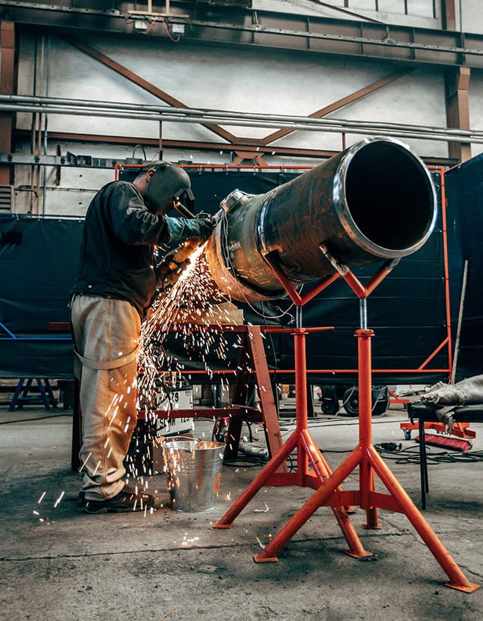 Industrial worker welding a fuel pipeline section
